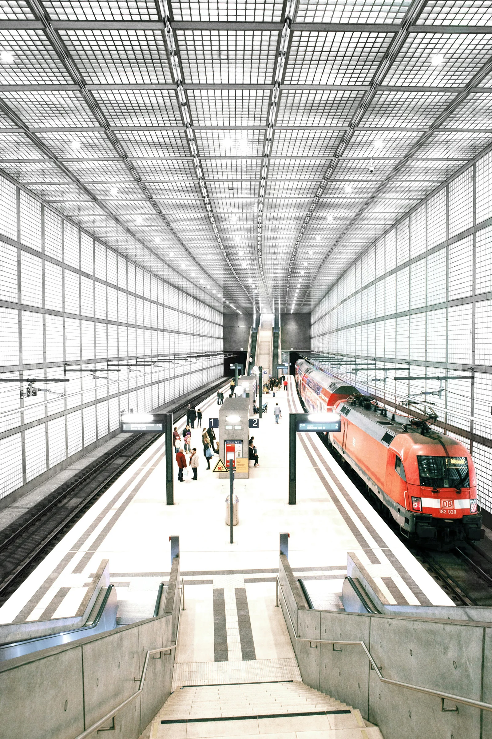 A European railway station with a passenger train and travelers in natural light